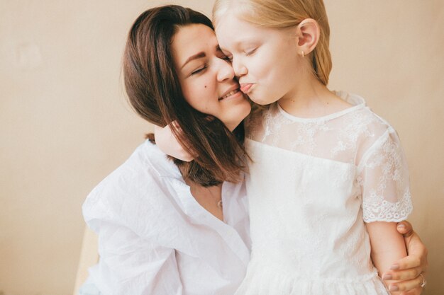 Ritratto dell'interno di stile di vita della figlia e della madre. Abbracci della madre con la sua piccola figlia divertente.