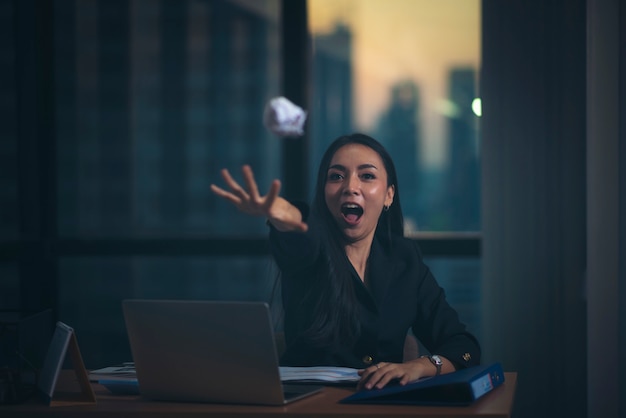 Ritratto dell&#39;ufficio di bella donna di affari insoddisfatta con i computer portatili che lanciano irosamente documenti alla macchina fotografica