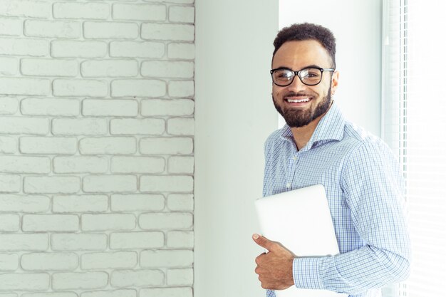 Ritratto dell'uomo afroamericano felice che usando il comruter del computer portatile