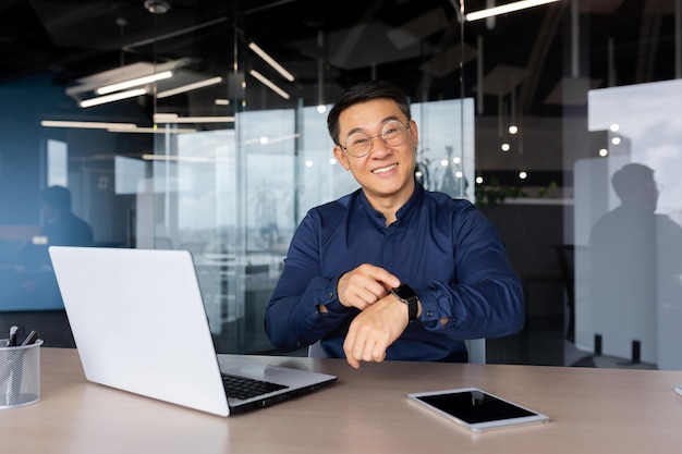 Ritratto dell'uomo asiatico sorridente riuscito all'interno dell'uomo d'affari dell'ufficio che sorride e che guarda l'obbiettivo
