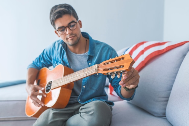 Ritratto dell&#39;uomo bello con la chitarra acustica che sorride e che osserva via