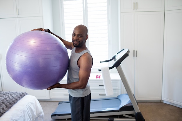 Ritratto dell'uomo che si esercita con la palla di forma fisica in camera da letto