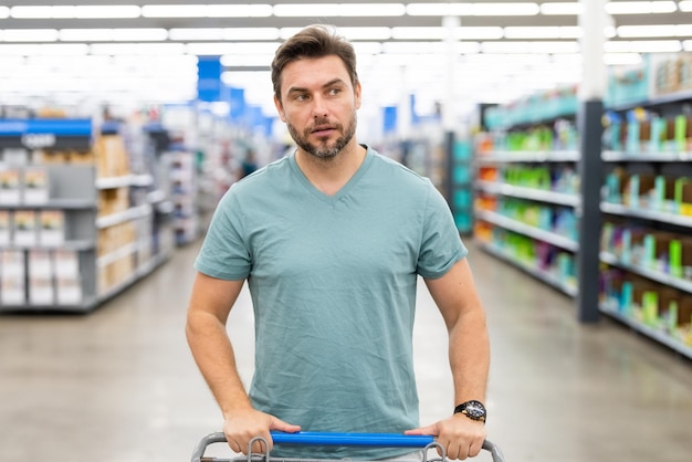 Ritratto dell'uomo con il carrello in un supermercato dello shopping del negozio e shopping di concetto del negozio di alimentari