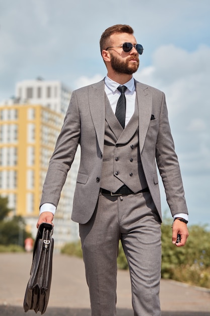 Ritratto dell'uomo d'affari caucasico bello con la borsa che va alla riunione d'affari