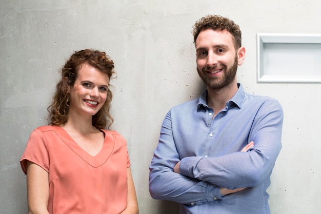 Ritratto dell'uomo e della donna sorridenti al muro di cemento