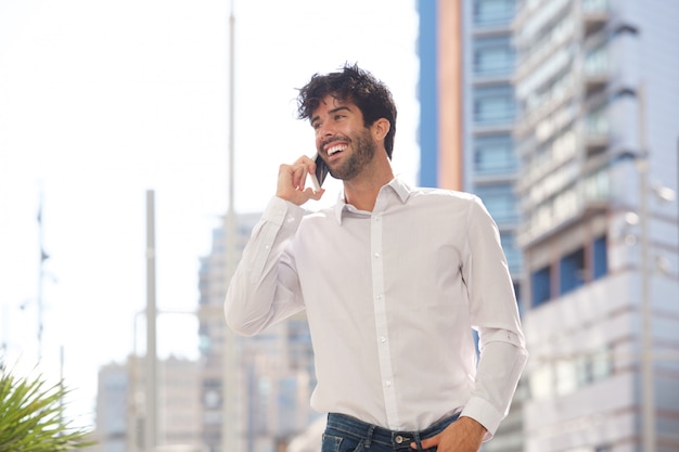 Ritratto dell&#39;uomo felice che ride e che parla sullo Smart Phone fuori