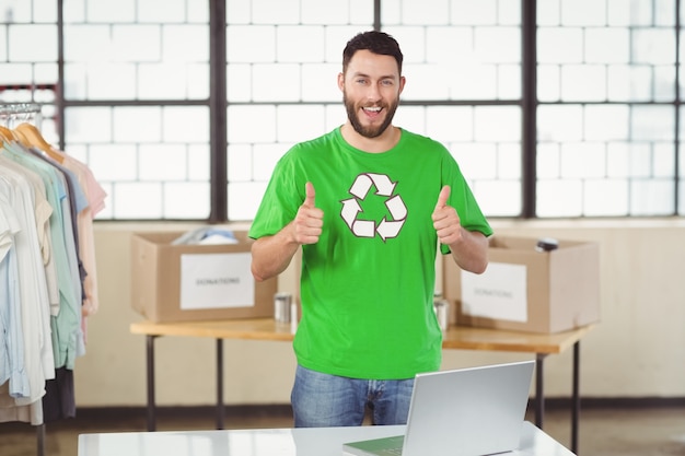 Ritratto dell&#39;uomo felice nel riciclaggio della maglietta di simbolo che mostra i pollici su