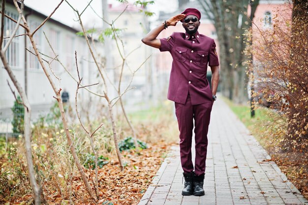 Ritratto dell'uomo militare afroamericano in uniforme rossa e saluto del berretto.