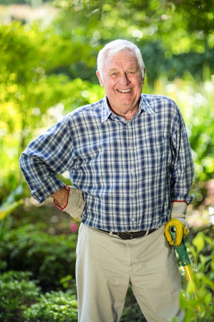 Ritratto dell'uomo senior con attrezzatura in giardino