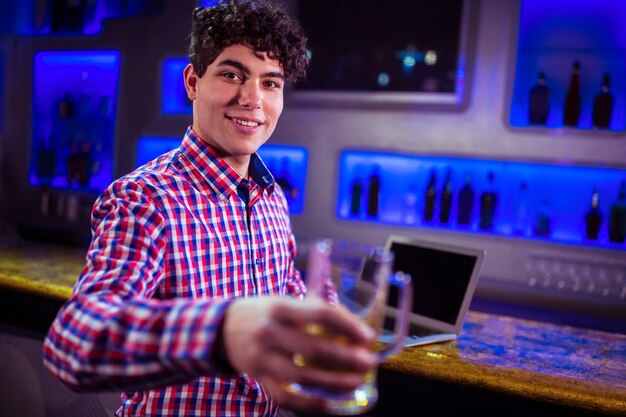 Ritratto dell'uomo sorridente che tiene il vetro di birra al contatore della barra