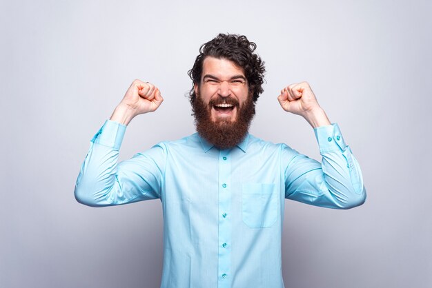 Ritratto dell'uomo stupito e felice in camicia blu che celebra la vittoria. OBBIETTIVO.