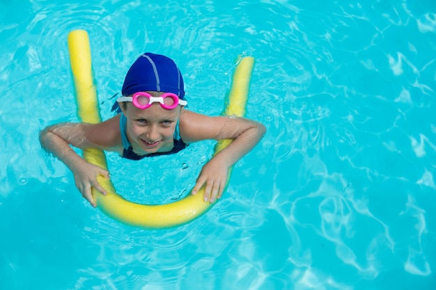 Ritratto della bambina che nuota con la tagliatella della piscina