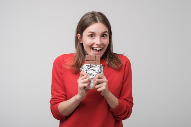 Ritratto della bella ragazza caucasica che mangia cioccolato