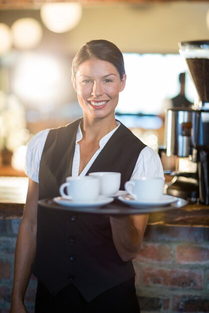 Ritratto della cameriera di bar che tiene un vassoio con le tazze di caffè