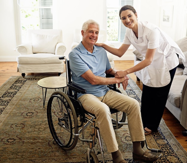 Ritratto della casa di cura e uomo disabile in sedia a rotelle benessere medico e supporto dell'infermiere Il caregiver felice aiuta il paziente con disabilità assistenza sanitaria senior e sorride per l'empatia nella clinica di riabilitazione