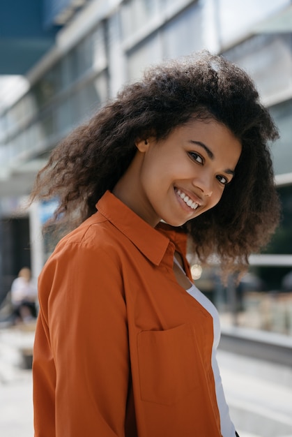 Ritratto della donna afroamericana sorridente con l'acconciatura riccia