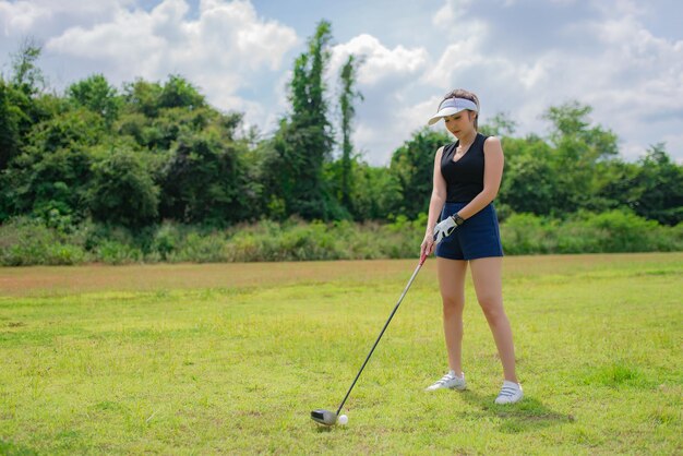 Ritratto della donna asiatica del golfista che tiene il legno di golf al concetto di donna felice del club del paese