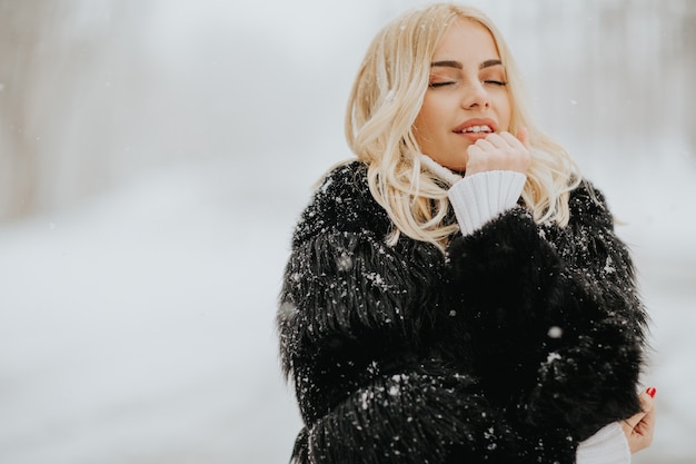 Ritratto della donna bionda fuori in cappotto di inverno della neve