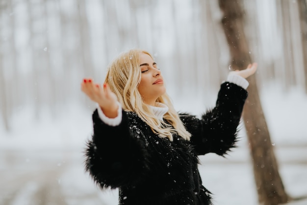 Ritratto della donna bionda fuori in cappotto di inverno della neve