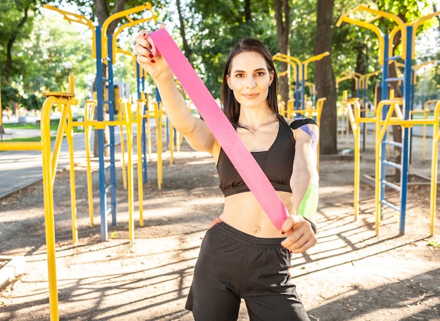 Ritratto della donna castana muscolare attraente che porta attrezzatura nera di sport