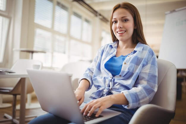 Ritratto della donna di affari che lavora al computer portatile in ufficio