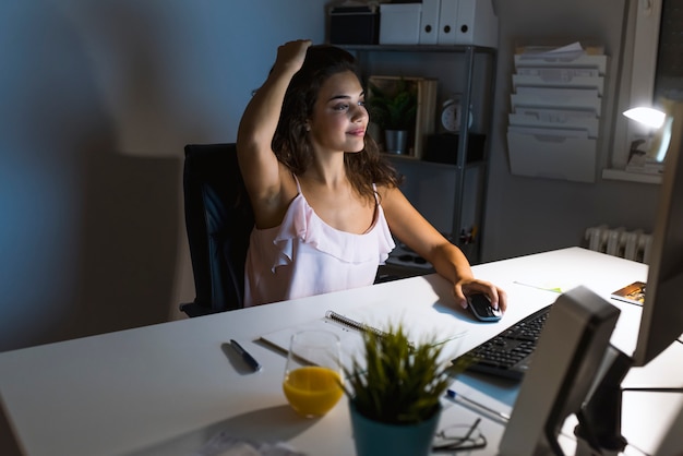 Ritratto della donna di affari che si siede alla scrivania e che pensa la soluzione mentre lavorando l