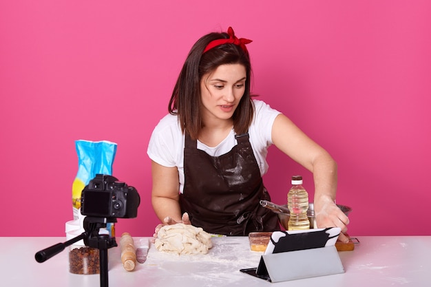 Ritratto della donna europea del brunette che cucina alla cucina