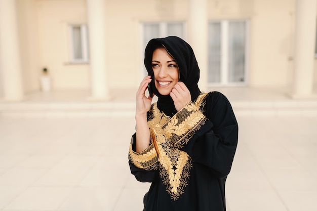 Ritratto della donna musulmana splendida con il sorriso a trentadue denti che sta all'aperto.