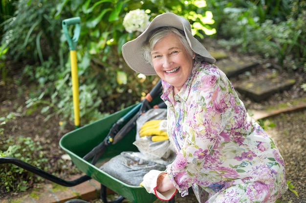 Ritratto della donna senior con la carriola in giardino