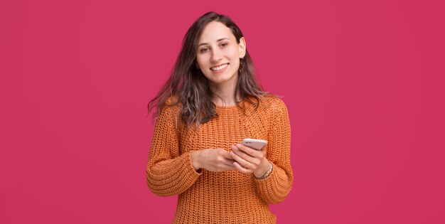 Ritratto della donna sorridente che porta maglione giallo e che tiene smartphone