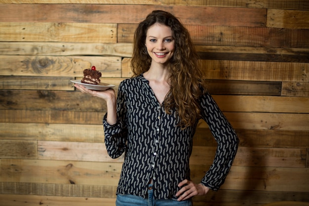 Ritratto della donna sorridente che tiene un piatto di pasticceria