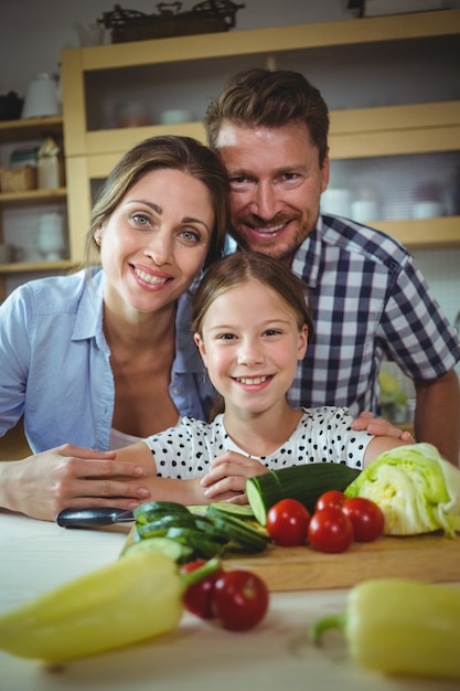 Ritratto della famiglia felice che si appoggia sul piano di lavoro della cucina