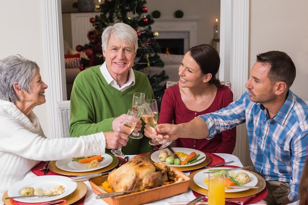 Ritratto della famiglia felice che tosta alla cena di natale