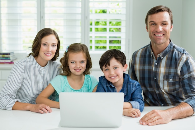 Ritratto della famiglia sorridente che utilizza computer portatile nel salone