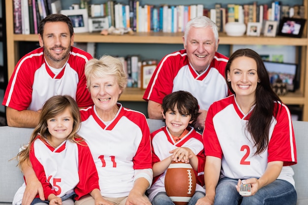 Ritratto della famiglia sorridente con i nonni che guardano la partita di football americano