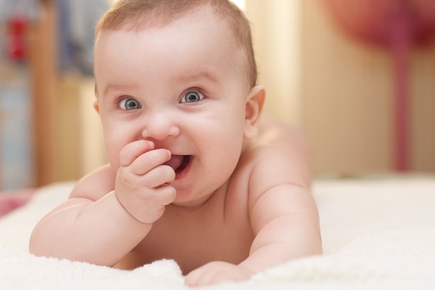 Ritratto della fine sana e divertente del bambino di 3 mesi su. carino neonato succhia il dito