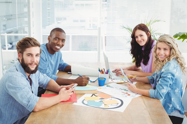 Ritratto della gente di affari sorridente che lavora mentre sedendosi allo scrittorio
