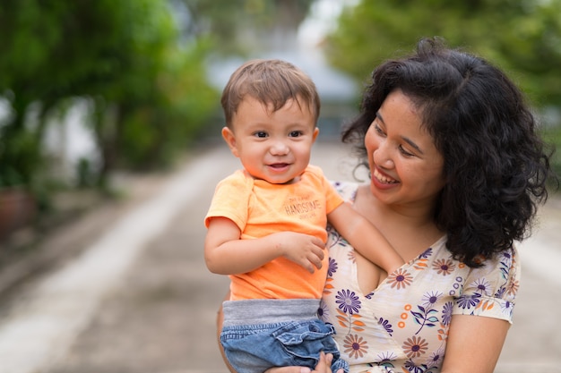 Ritratto della madre asiatica felice e del figlio multietnico del bambino che legano insieme all'aperto