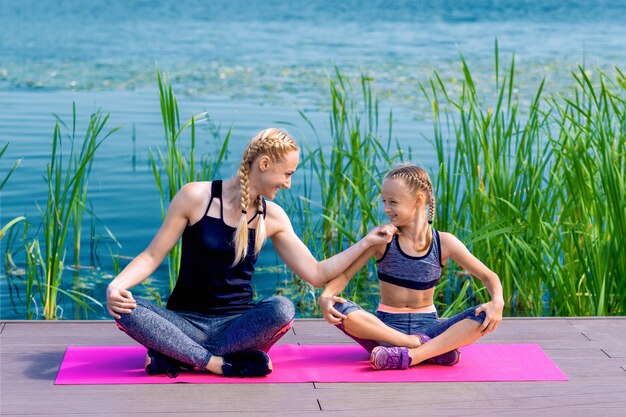 Ritratto della madre e della figlia che si siedono sulla stuoia di yoga