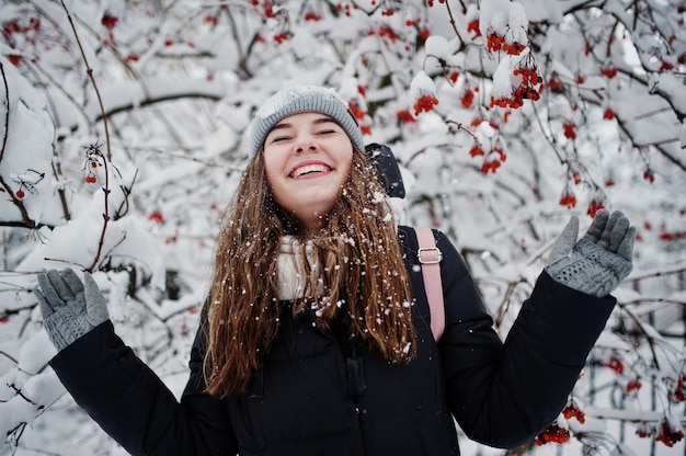 Ritratto della ragazza al giorno nevoso di inverno vicino agli alberi innevati.