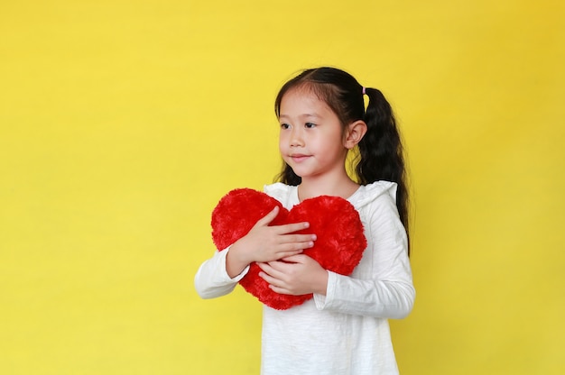 Ritratto della ragazza asiatica sorridente che tiene un cuore rosso