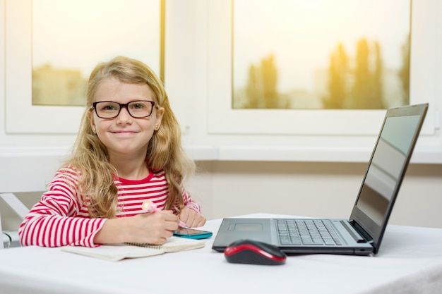 Ritratto della ragazza che per mezzo di un computer portatile, smartphone