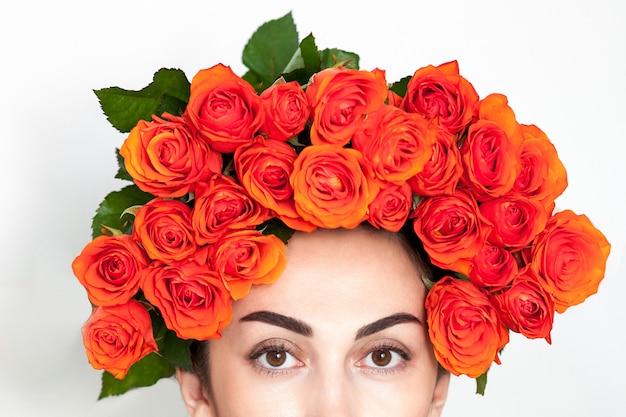 Ritratto della ragazza dai capelli rossi che ride con rose arancioni