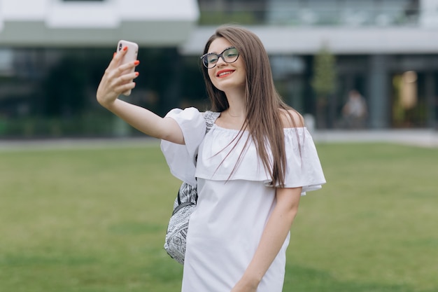 Ritratto della ragazza dell'adolescente dello studente che prende selfie nell'università all'aperto