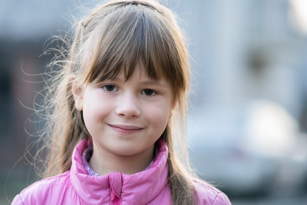 Ritratto della ragazza felice del bambino in vestiti caldi in autunno all'aperto.