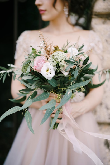 Ritratto della sposa con un mazzo di fiori legato con nastri