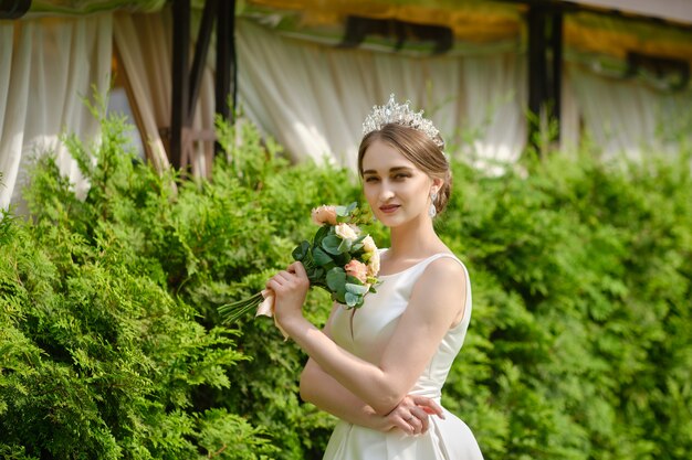 Ritratto della sposa graziosa con la coroncina nel padiglione vicino all'aperto di cerimonia dei capelli