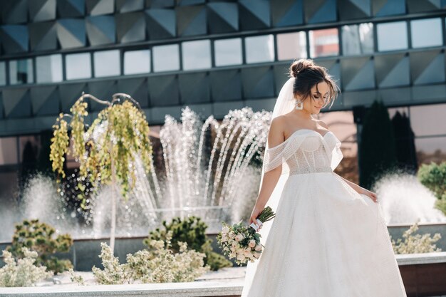 Ritratto della sposa in città vicino alla fontana. Una splendida giovane sposa con i capelli ricci. Giorno del matrimonio. . Bellissimo ritratto della sposa senza lo sposo.