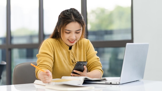 Ritratto della studentessa asiatica che studia alla biblioteca dell'università