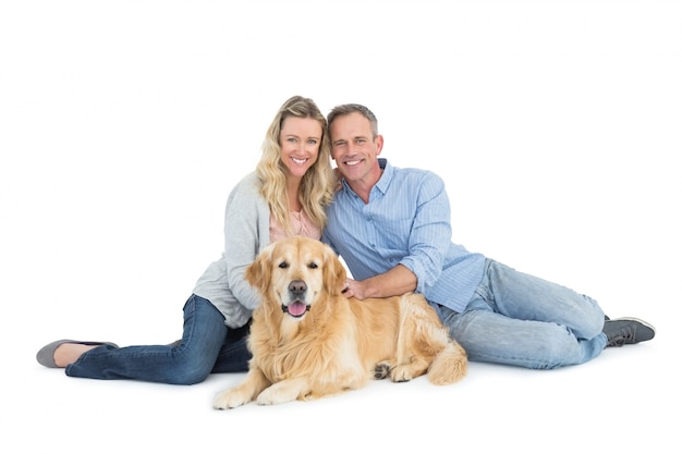 Ritratto delle coppie sorridenti che si siedono insieme al loro cane